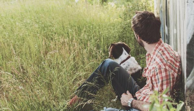 Un uomo e un cane seduti su un prato