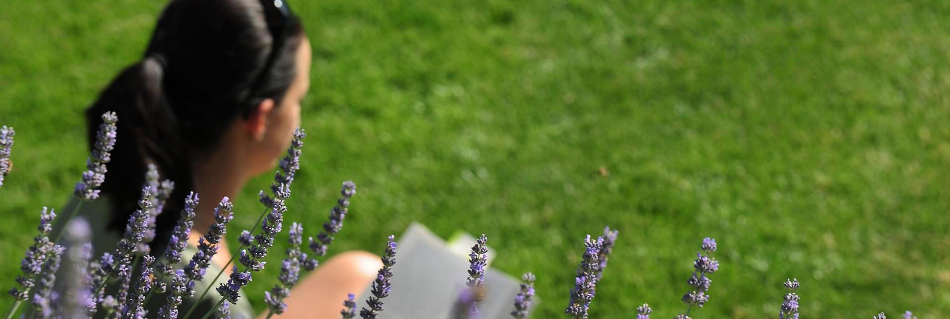 Una donna legge seduta su un piato fiorito